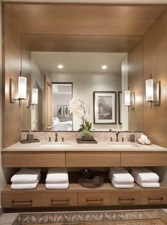 a large bathroom with two sinks, mirrors and towels on the counter top in front of it