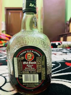 a bottle of old monk liquor sitting on top of a carpeted floor next to a wooden door