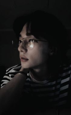 a woman with glasses is sitting in the dark