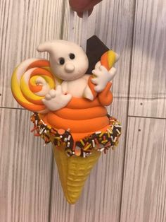 an ice cream cone with a small plastic figure on it's top, holding a candy bar