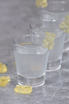 three glasses filled with water and yellow gummy bears