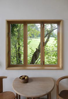 a wooden table sitting under a window next to a bowl of fruit on top of it