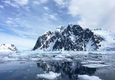 ice floes floating on the water in front of snow covered mountains