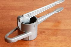 a pair of tongs sitting on top of a wooden table next to a bottle opener