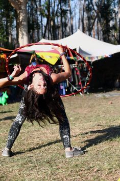 a woman doing a handstand on the ground in front of tents and trees
