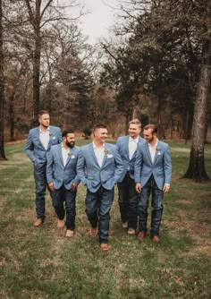 a group of men standing next to each other on top of a lush green field