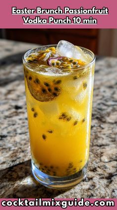 an orange drink in a tall glass with ice and fruit on the rim, sitting on a granite counter top