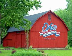 a red barn with the word oko written on it's side in front of trees