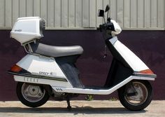 a motor scooter parked in front of a building with a purple wall behind it
