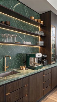 a kitchen with green marble counter tops and wooden cabinets, along with brass - plated faucets