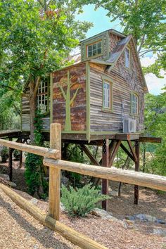 a tree house built into the side of a wooden fence in front of some trees