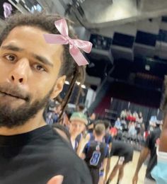 a man with a pink bow on his head standing in front of a basketball court
