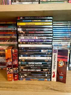 a stack of dvds sitting on top of a wooden shelf