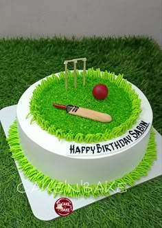 a birthday cake with grass and a cricket ball on top, in the shape of a circle