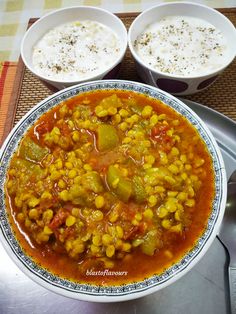 two bowls filled with soup on top of a metal tray next to another bowl full of food
