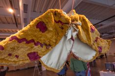 a large stuffed animal hanging from the ceiling in a room with other people standing around
