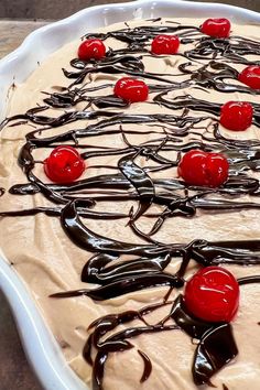 a cake with chocolate and cherries on top in a pan sitting on a table