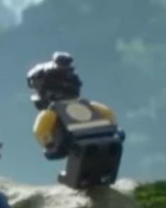 two legos are standing on top of a hill and one is holding a yellow frisbee