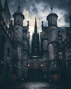 an old castle with stairs leading up to the entrance and dark clouds in the sky