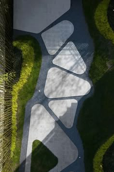 an aerial view of a walkway in the middle of some grass and bushes, looking down at it