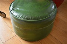 a green leather ottoman sitting on top of a wooden floor