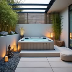 an outdoor hot tub in the middle of a patio with lights around it and bamboo trees on either side