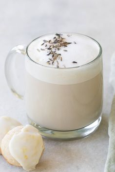 a glass mug filled with white liquid next to a cookie