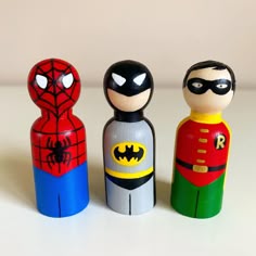 three wooden toy figurines are lined up on a table