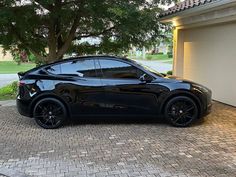 a black sports car parked in front of a house