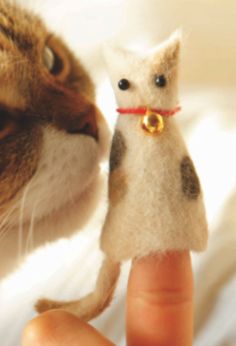 a hand holding a tiny toy cat in it's right hand and another miniature animal on its left