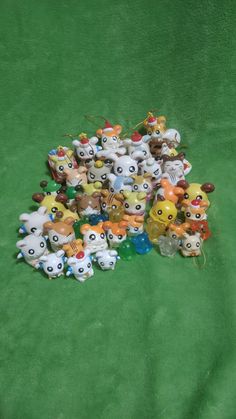 a pile of small stuffed animals sitting on top of a green cloth covered floor next to each other