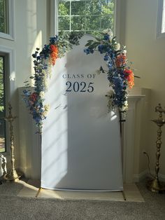 a class of 205 sign in front of a window with flowers and foliage on it