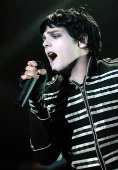 a male singer in a striped shirt singing into a microphone