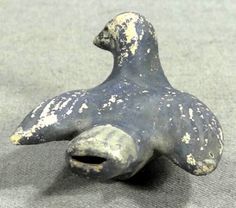 an old ceramic bird sitting on top of a gray cloth covered tablecloth with white spots