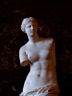 a statue of a woman with no shirt on, in front of a black background