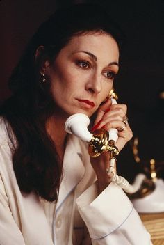 a woman sitting at a table with a phone in her hand and looking off to the side