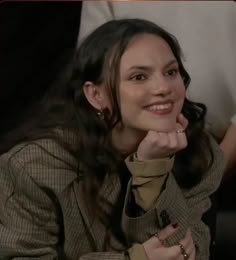 a woman sitting down with her hand on her chin