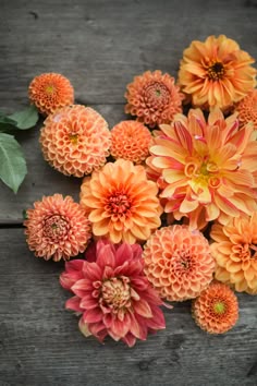 an arrangement of orange and red flowers on a wooden surface