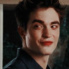 a close up of a person wearing a black shirt and red lipstick in front of a window