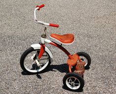 an orange and white tricycle sitting on the ground