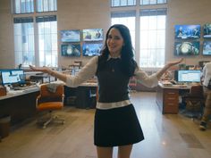 a woman standing in an office with her arms outstretched