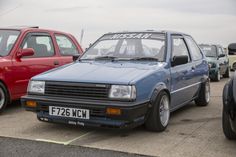 several cars are parked in a parking lot with one red car and the other blue
