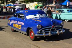 the cars are parked on the side of the road in front of people and buildings