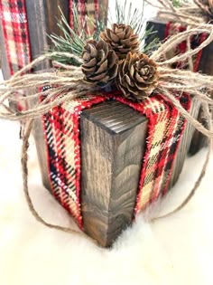 some pine cones are sitting on top of a wooden box with plaid ribbon and twine