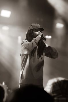 a black and white photo of a man with dreadlocks singing into a microphone