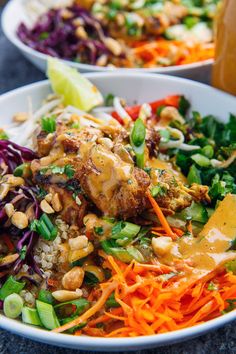 two white bowls filled with different types of vegetables and meat on top of each other