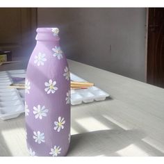 a purple vase sitting on top of a wooden table next to an egg carton