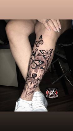 a woman's leg with tattoos on it and butterflies flying around her legs,