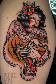 a woman with a tiger tattoo on her arm and chest is holding onto the head of a cat