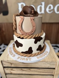 a three tiered cake decorated with cow print and horseshoes on it's sides